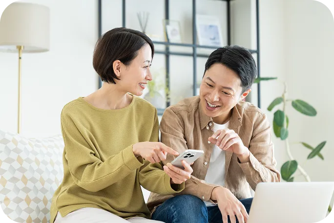 リビングでスマートフォンを見ながら話すカップル